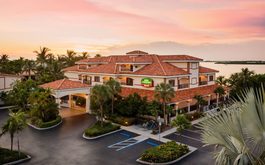 Aerial view of Courtyard by Marriott Key West at dusk, surrounded by palms and terracotta rooftops.