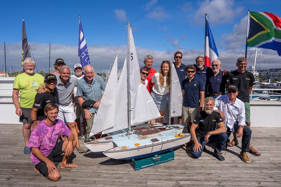 GGR2026 skippers and guests examine a scale model of Donald Crowhurst's trimaran Teignmouth Electron, honouring the original race's complex history as a new fleet heads to sea.