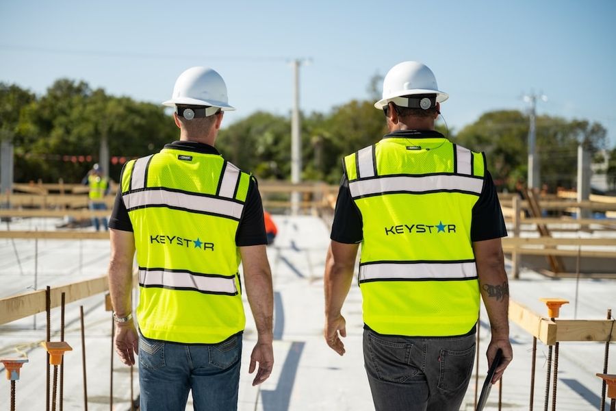 Two Keystar Construction team members in hard hats and safety vests on the job site