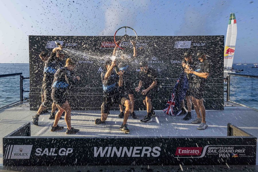 Winner! Peter Burling, co-CEO and driver of New Zealand SailGP Team on the podium as they spray Barons De Rothschild Champagne in celebration with the New Zealand SailGP Team on Race Day 2 of the Emirates Dubai Sail Grand Prix presented by P&O Marinas in Dubai, UAE. Sunday 24 November 2024. Photo: Christopher Pike for SailGP. Photo credit: SailGP