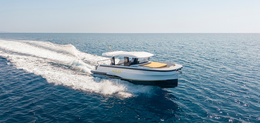 The Marcopolo MP12 underway, its wide hardtop sheltering the open cockpit while the forward sunpad provides a separate lounging area.