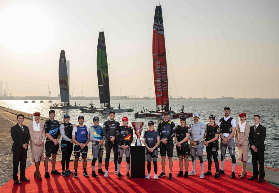 SailGP athletes are joined by Emirates flight attendants as they stand for a photo with the Rolex SailGP Championship trophy in front of the Emirates Great Britain SailGP Team, Australia SailGP Team and Red Bull Italy SailGP Team F50 catamarans. (L-r) Peter Burling, co-CEO and driver of New Zealand SailGP Team, Anna Weis, grinder and jib trimmer of USA SailGP Team, Ruggero Tita, driver of Red Bull Italy SailGP Team, Martine Grael, driver of Mubadala Brazil SailGP Team, Erik Heil, driver of Germany SailGP Team, Nicole van der Velden, strategist of Spain SailGP Team, Hannah Mills, strategist of Emirates Great Britain SailGP Team, Tom Slingsby, driver of Australia SailGP Team, Katja Salskov-Iversen, strategist of ROCKWOOL Denmark SailGP Team, Quentin Delapierre, driver of France SailGP Team, Maud Jayet, strategist of Switzerland SailGP Team, and Giles Scott, driver of Canada NorthStar SailGP Team. Emirates Dubai Sail Grand Prix presented by P&O Marinas in Dubai, UAE. Friday 22 November 2024. Photo: Ricardo Pinto for SailGP. Handout image supplied by SailGP. Photo credit: SailGP