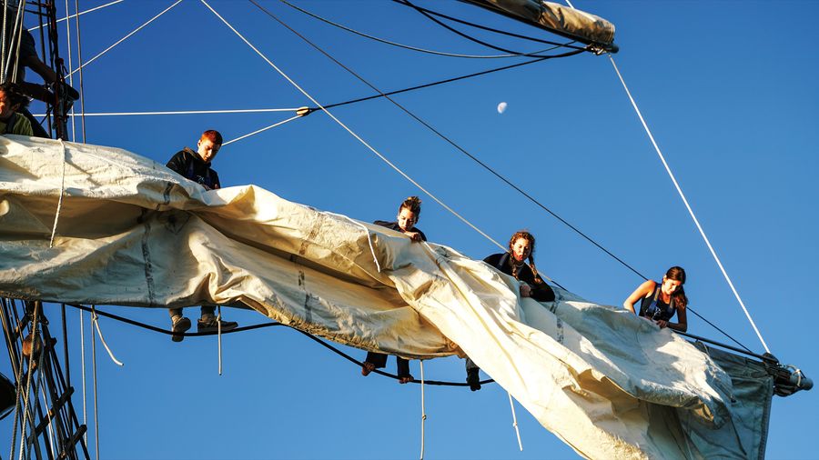 Young trainees stowing the ‘course’ (sail) – heavy work