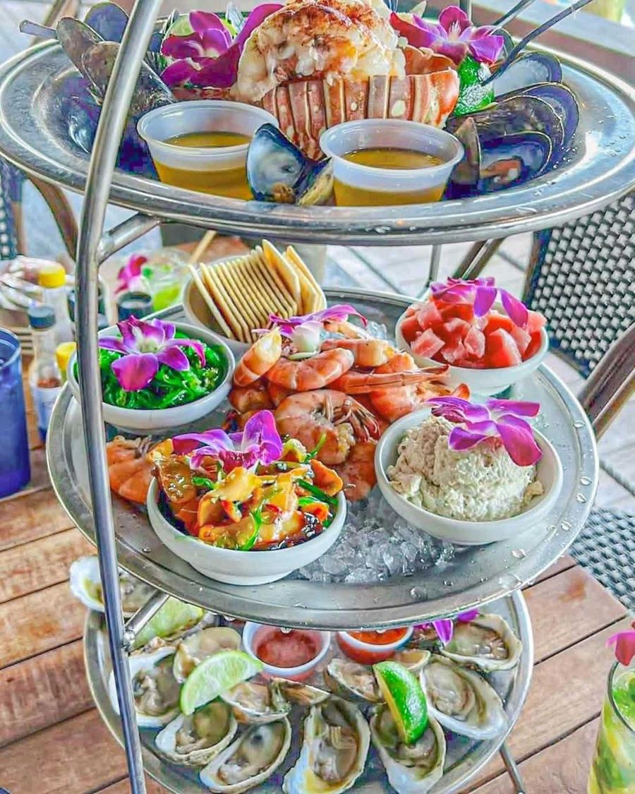 A three-tier seafood tower loaded with lobster, shrimp, poke, oysters and orchids at A&B Marina