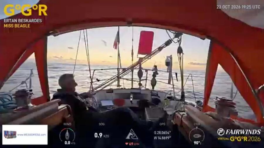 Ertan Beskardes sitting in the cockpit of Miss Beagle under an orange spray hood at sunset, with a calm sea behind