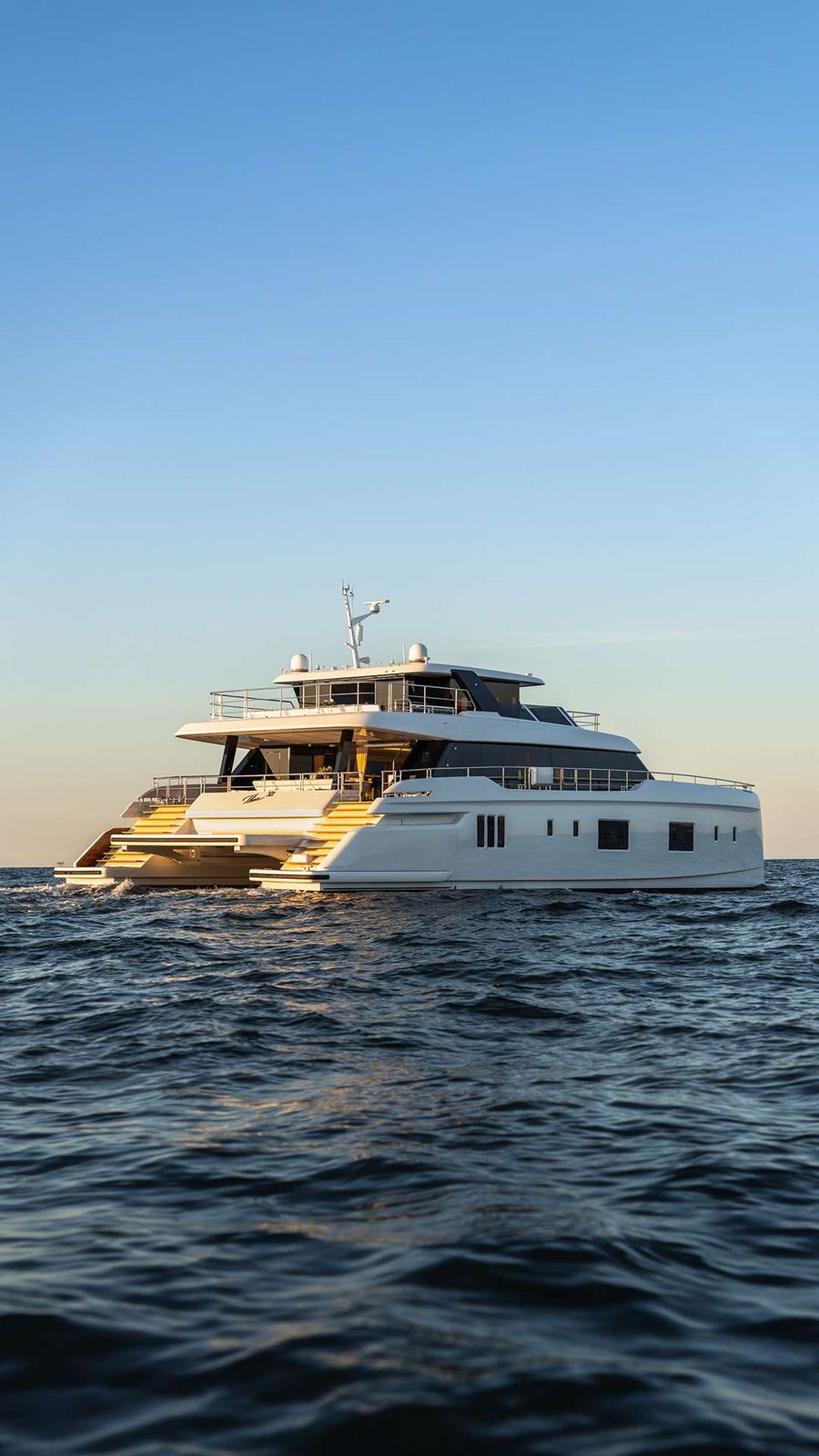A Sunreef Yacht cruises the open ocean under a clear blue sky.